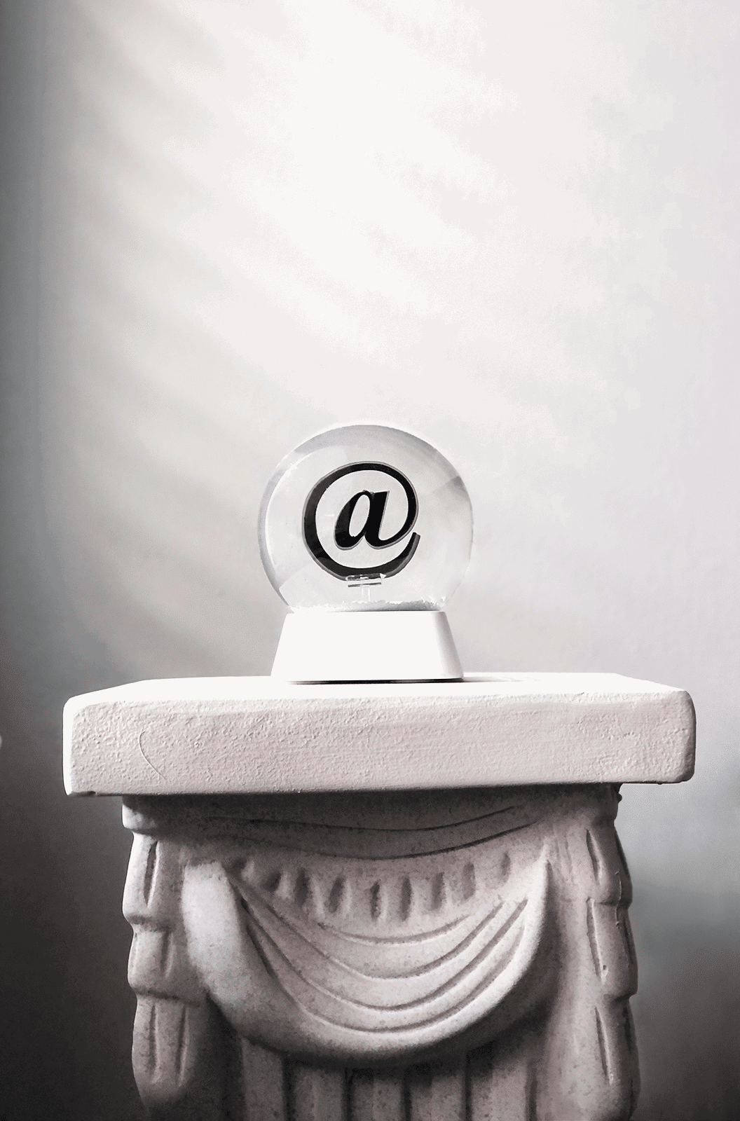 Pure Products USA's @ snow globe on display on marble pedestal. 4 inch glass snow globe.