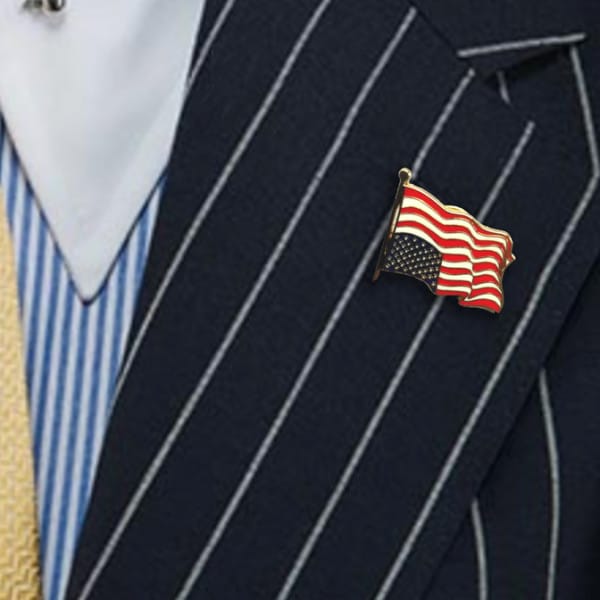 Ligorano Reese's Dress For Distress upside down American flag pin on lapel. Gold enamel. Butterfly clutch. From Pure Products USA.